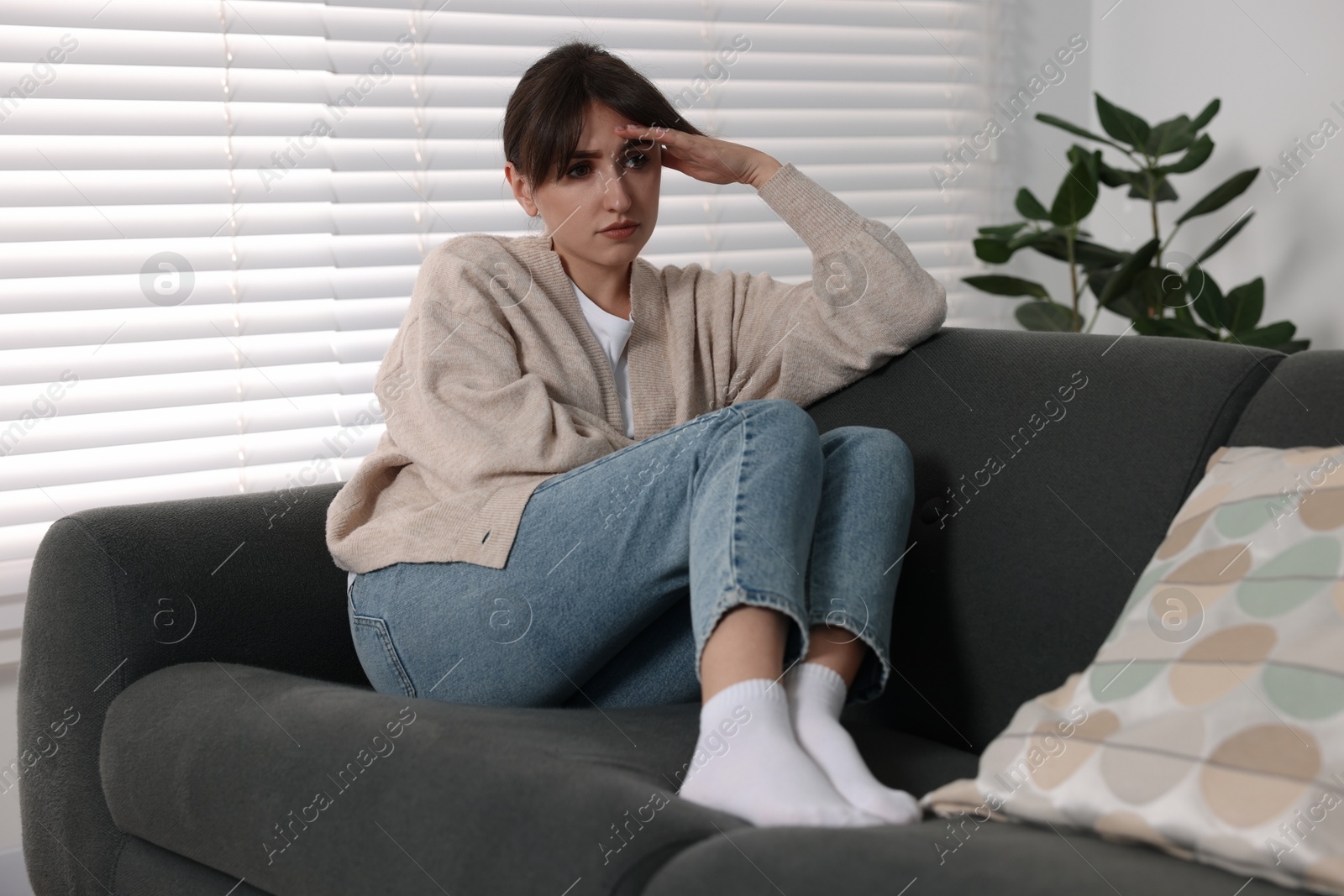 Photo of Loneliness concept. Sad woman sitting on sofa at home