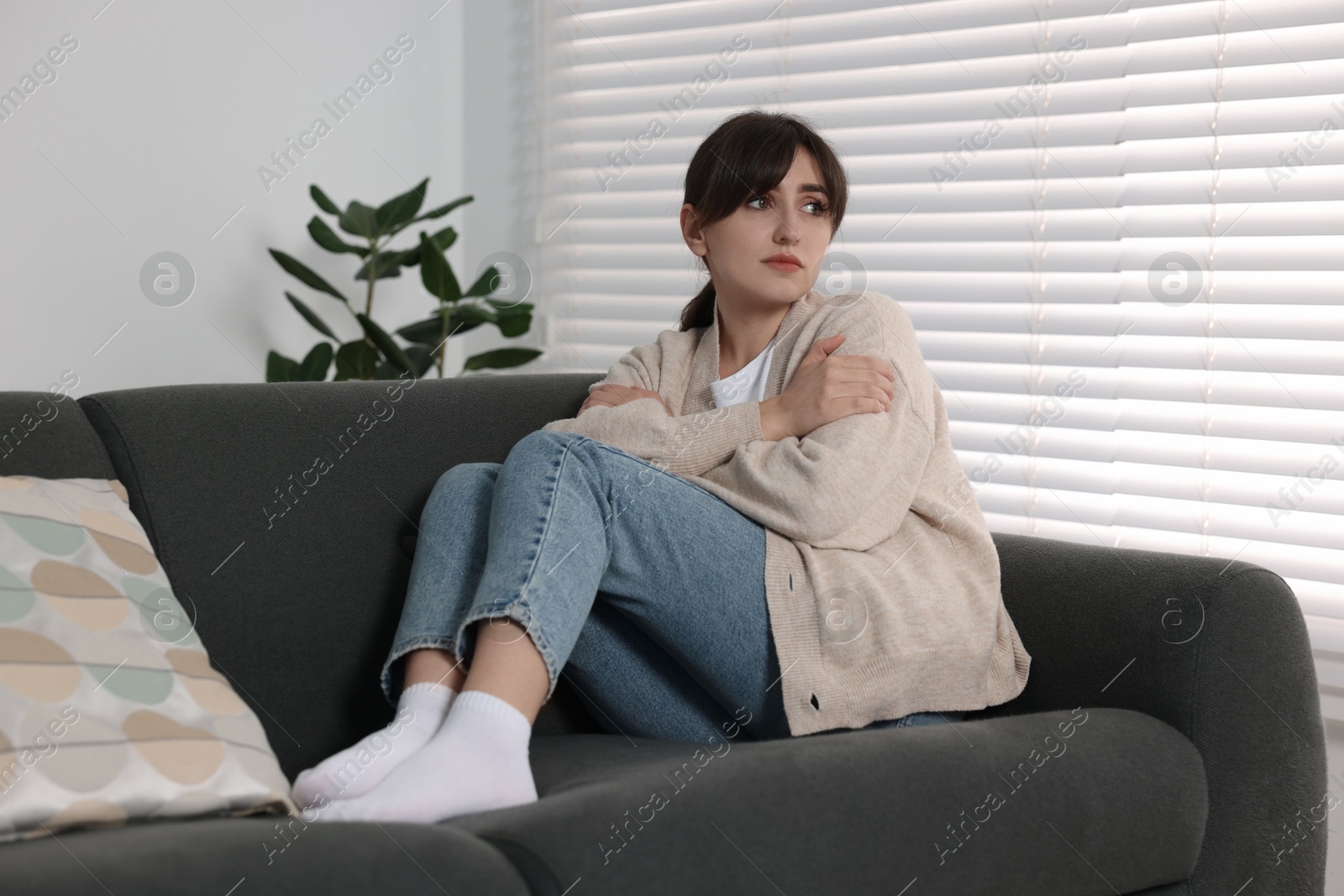 Photo of Loneliness concept. Sad woman sitting on sofa at home