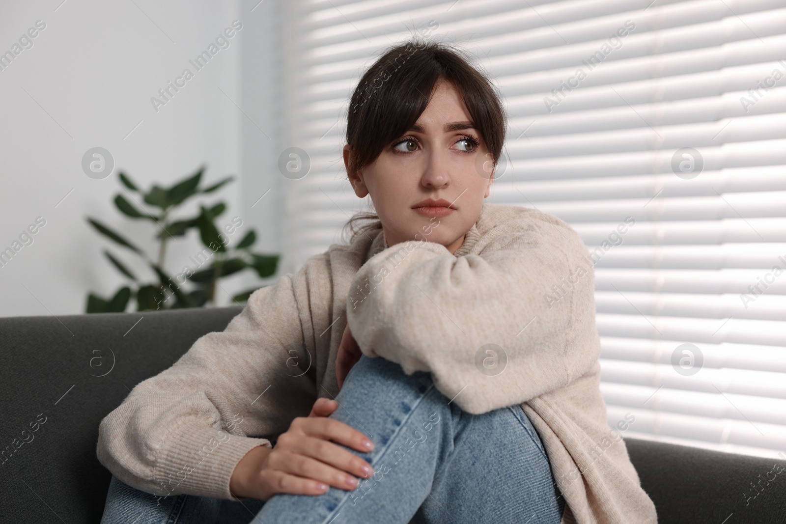 Photo of Loneliness concept. Sad woman sitting on sofa at home