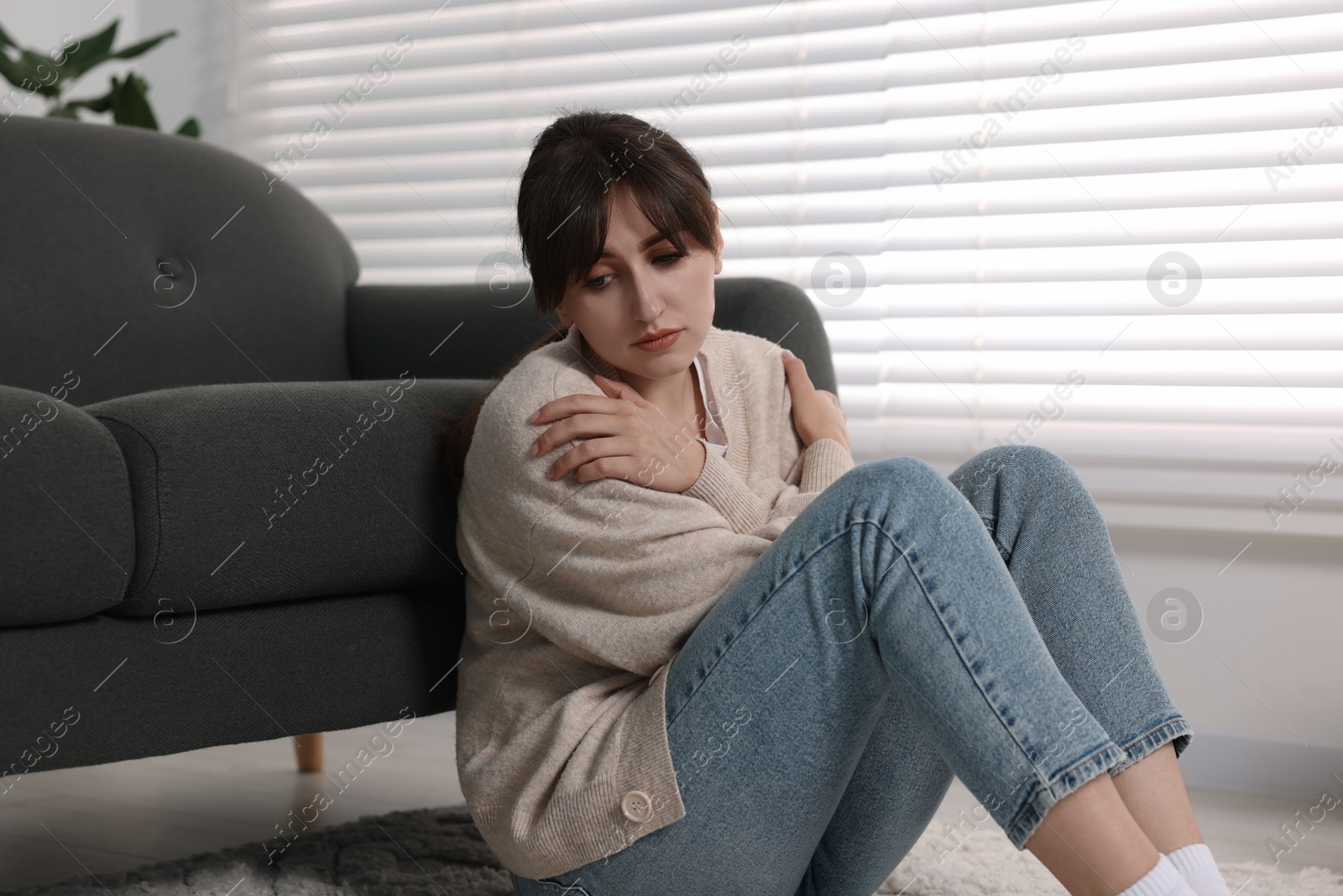 Photo of Loneliness concept. Sad woman sitting on floor at home