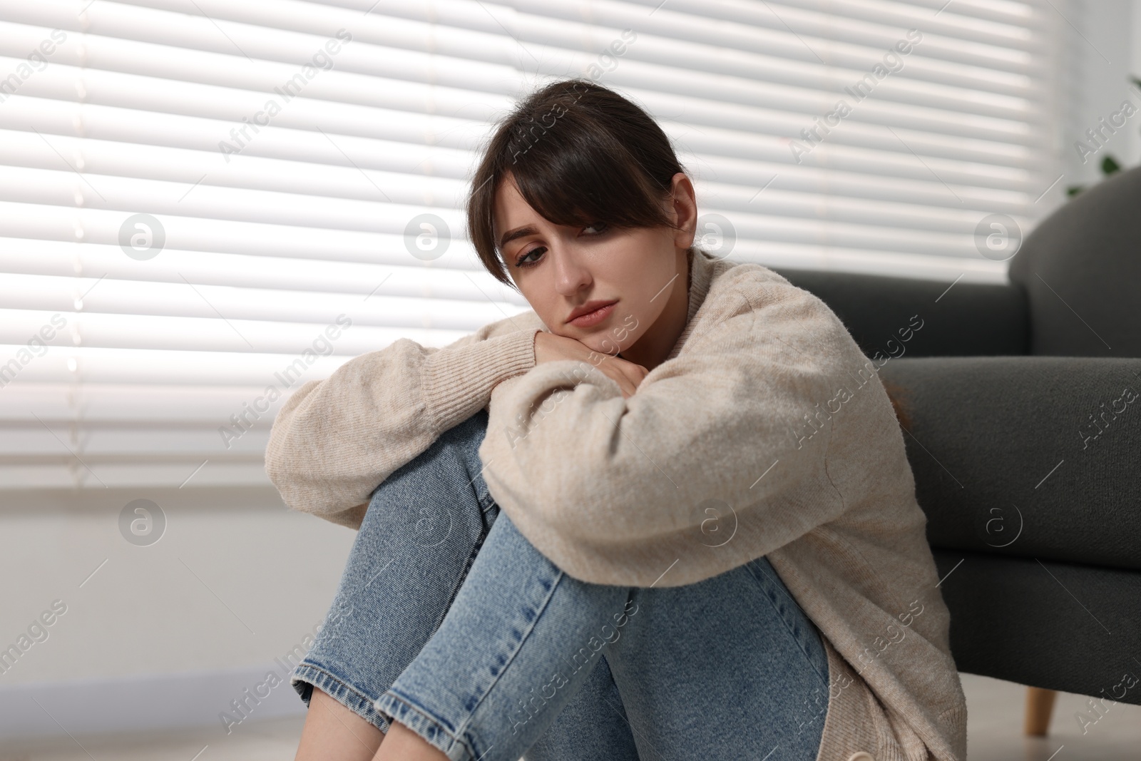 Photo of Loneliness concept. Sad woman sitting on floor at home