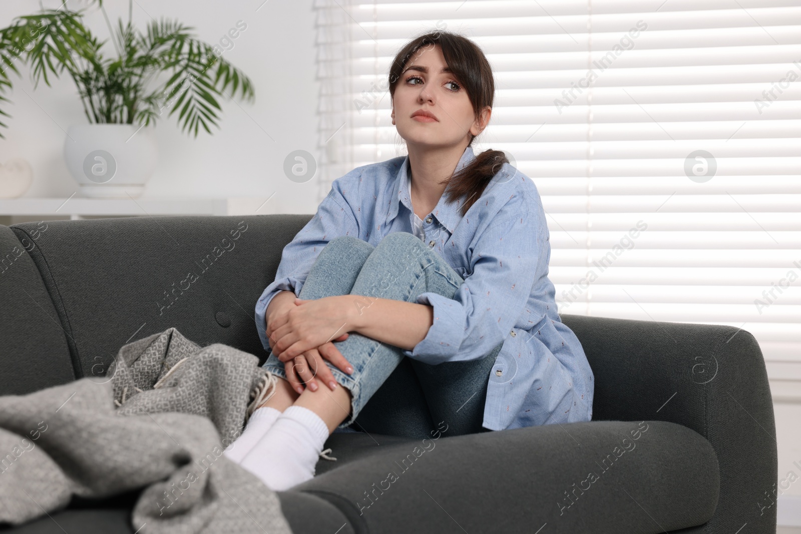 Photo of Loneliness concept. Sad woman sitting on sofa at home