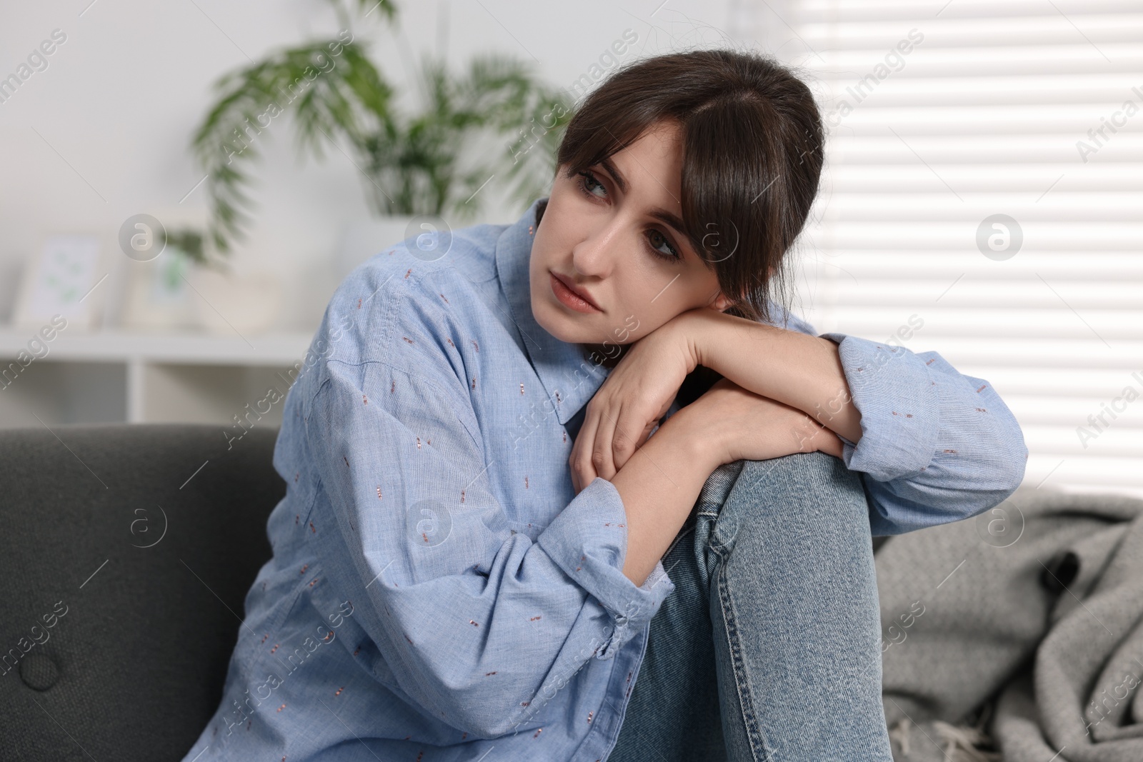 Photo of Loneliness concept. Sad woman sitting on sofa at home