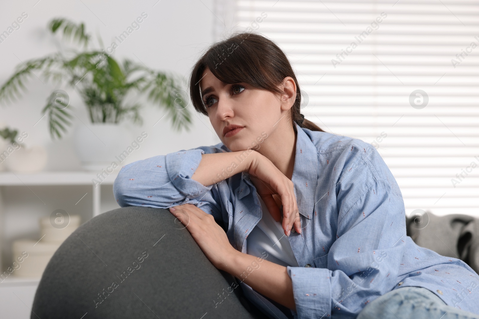 Photo of Loneliness concept. Sad woman sitting on sofa at home