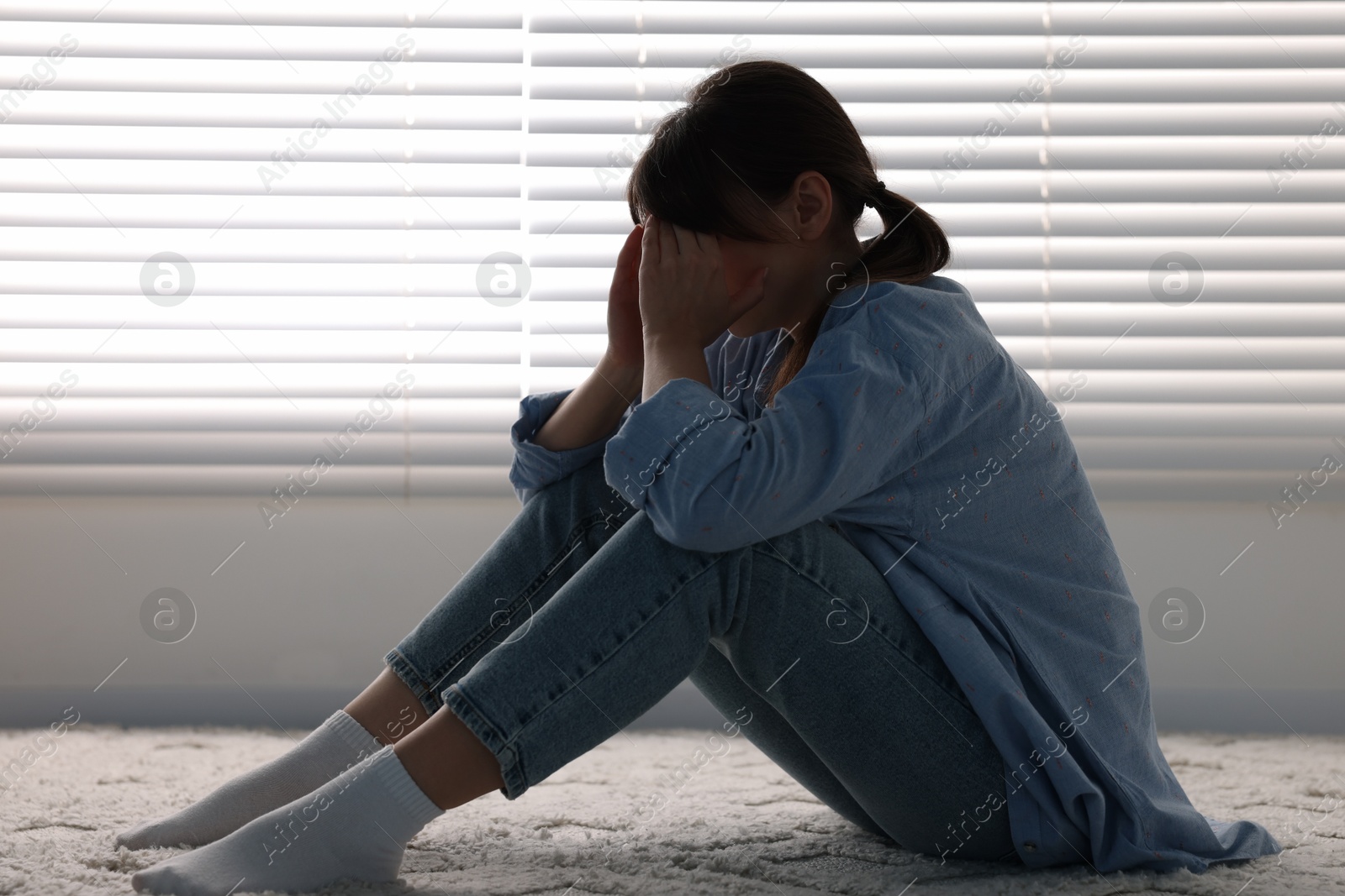 Photo of Loneliness concept. Sad woman sitting on floor at home