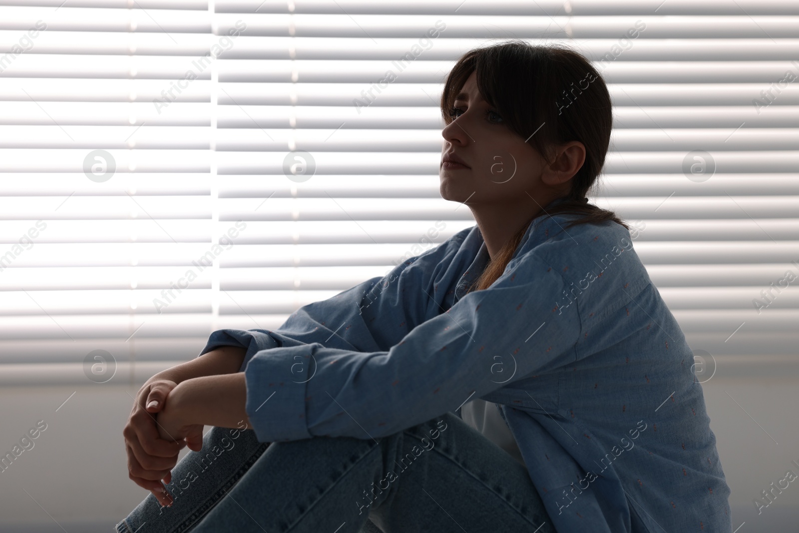 Photo of Loneliness concept. Sad woman sitting on floor at home