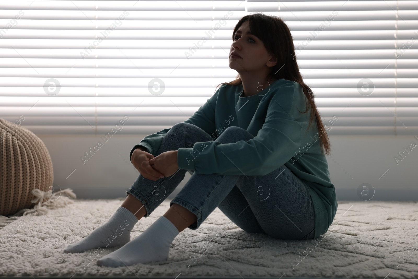 Photo of Loneliness concept. Sad woman sitting on floor at home