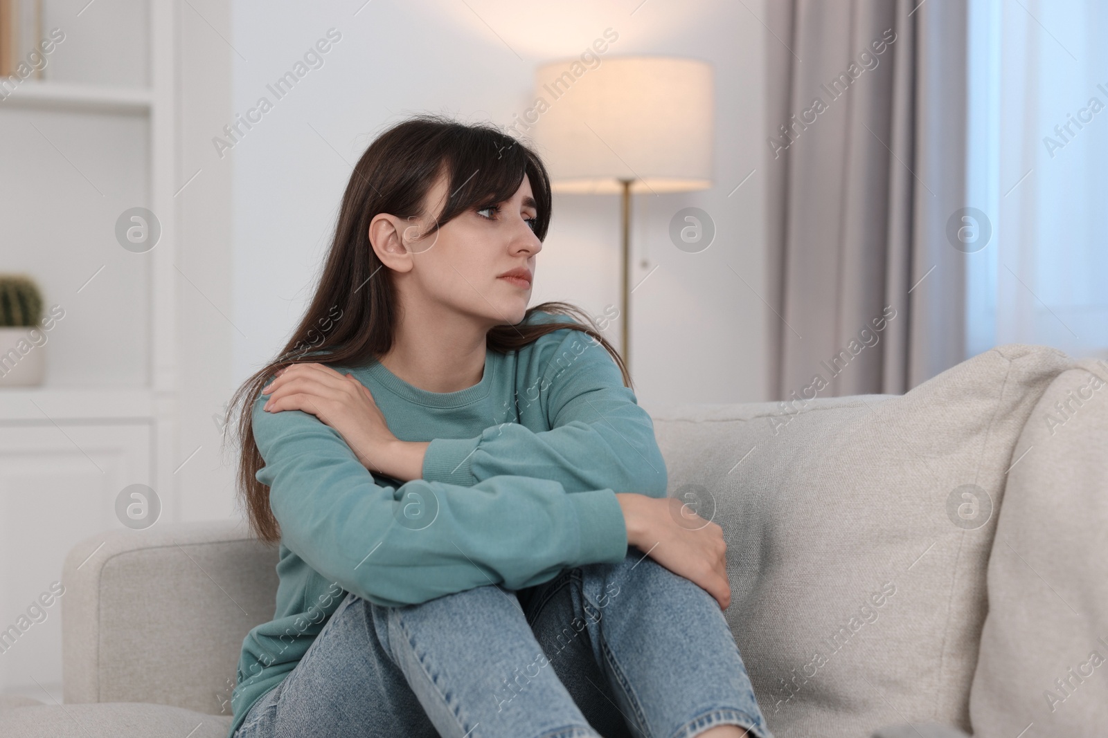 Photo of Loneliness concept. Sad woman sitting on sofa at home