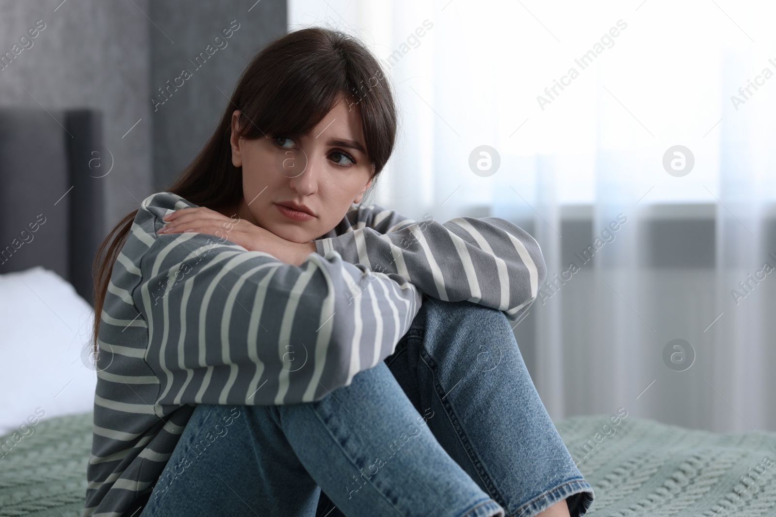 Photo of Loneliness concept. Sad woman sitting on bed at home