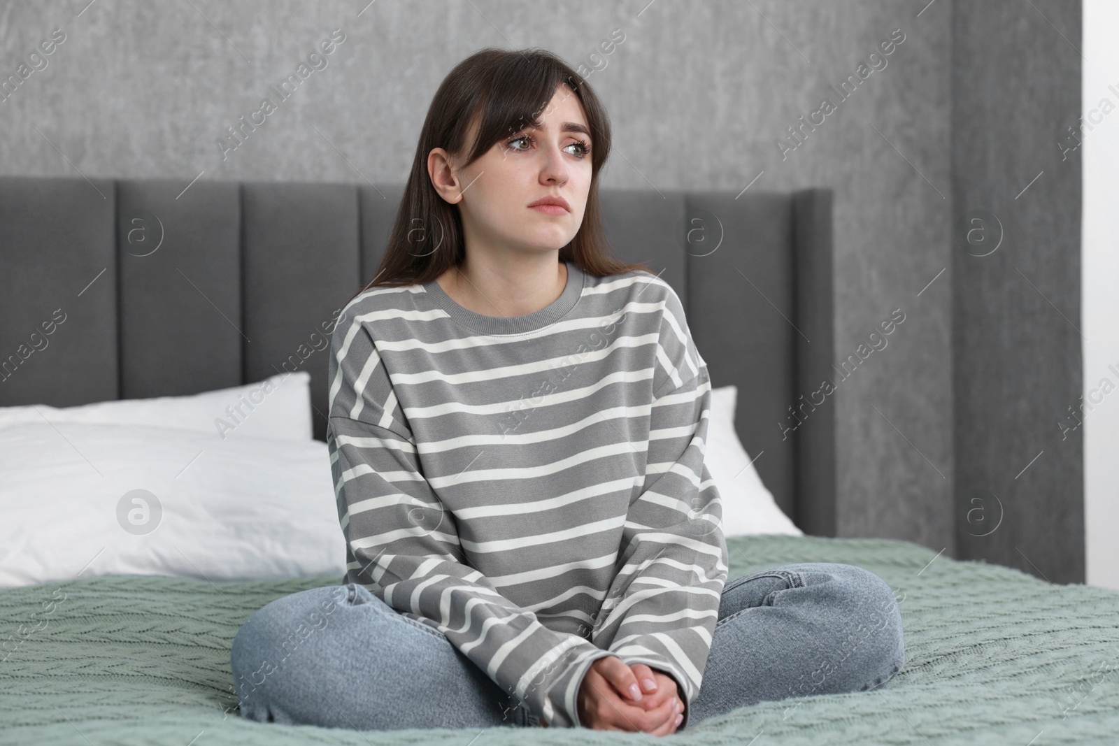 Photo of Loneliness concept. Sad woman sitting on bed at home