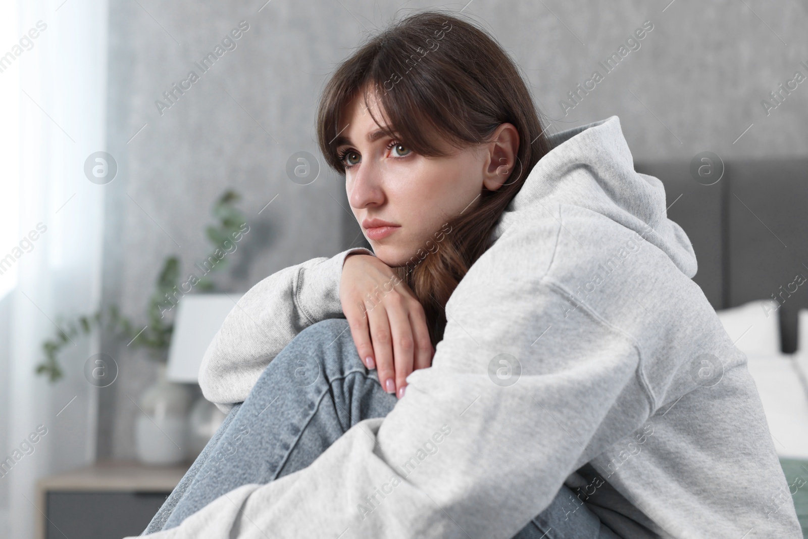 Photo of Loneliness concept. Sad woman sitting on bed at home