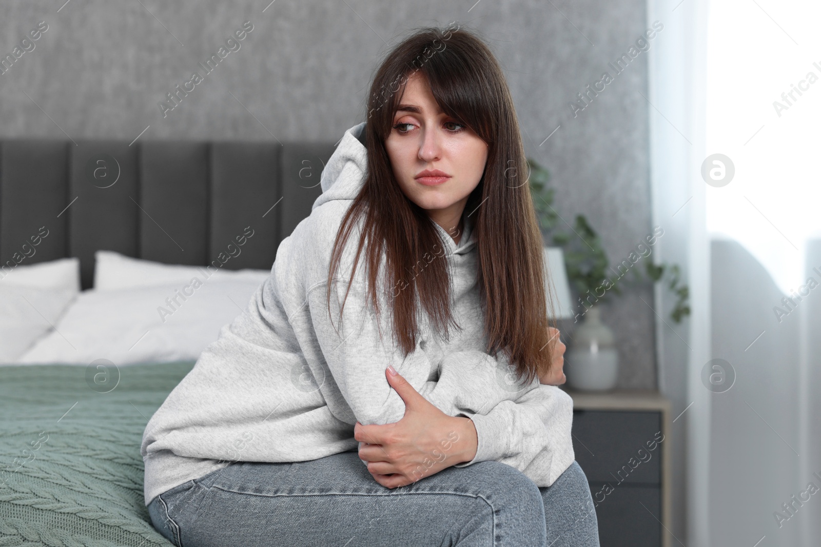 Photo of Loneliness concept. Sad woman sitting on bed at home