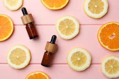 Photo of Aromatherapy. Different essential oils and citrus fruits on pink wooden table, flat lay