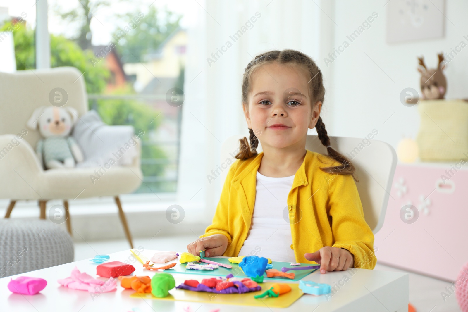 Photo of Portrait of little girl at table with play dough in kindergarten