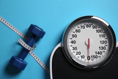 Photo of Scale, dumbbells and measuring tape on light blue background, flat lay