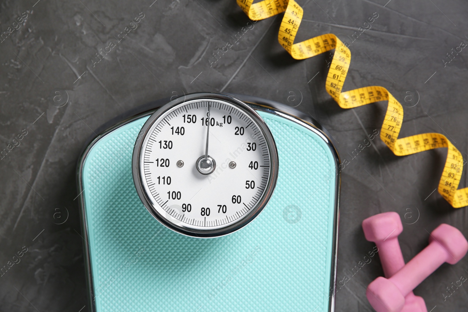 Photo of Bathroom scale, measuring tape and dumbbells on grey textured background, flat lay