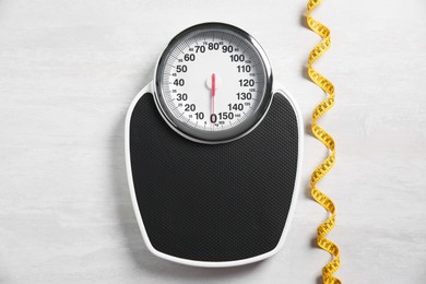 Photo of Scale and measuring tape on white wooden background, flat lay