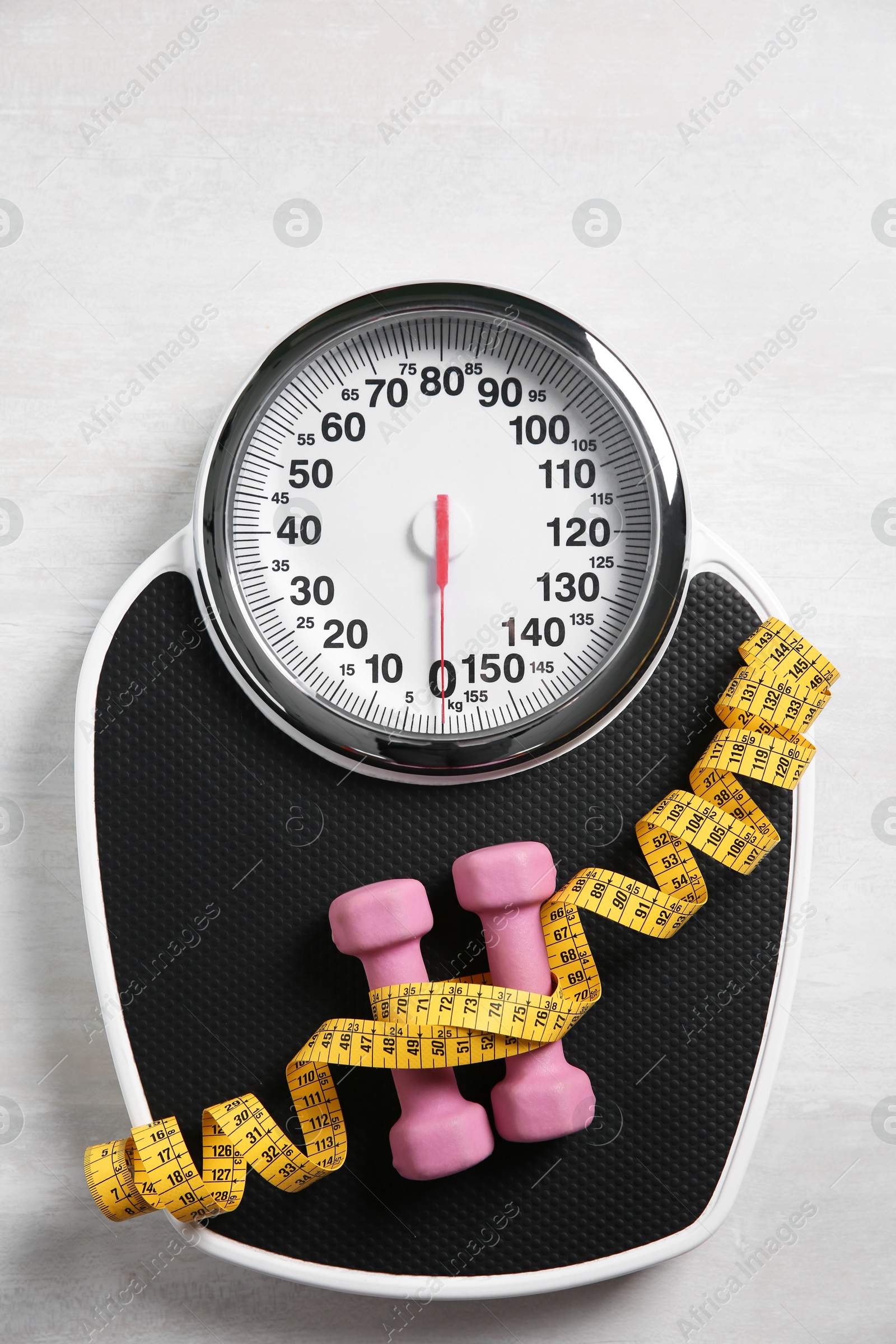 Photo of Bathroom scale, measuring tape and dumbbells on white wooden background, flat lay