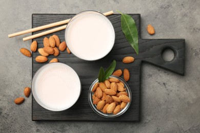 Photo of Glasses of almond milk and almonds on grey table, top view