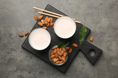 Photo of Glasses of almond milk and almonds on grey table, top view