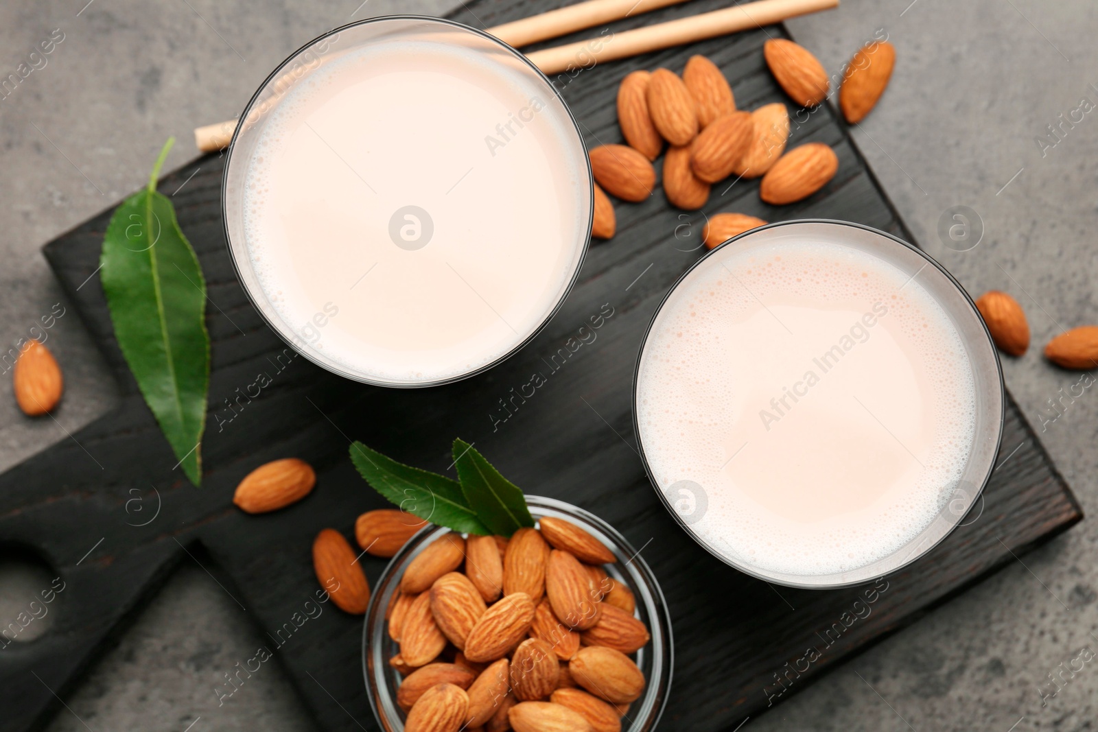 Photo of Glasses of almond milk and almonds on grey table, top view