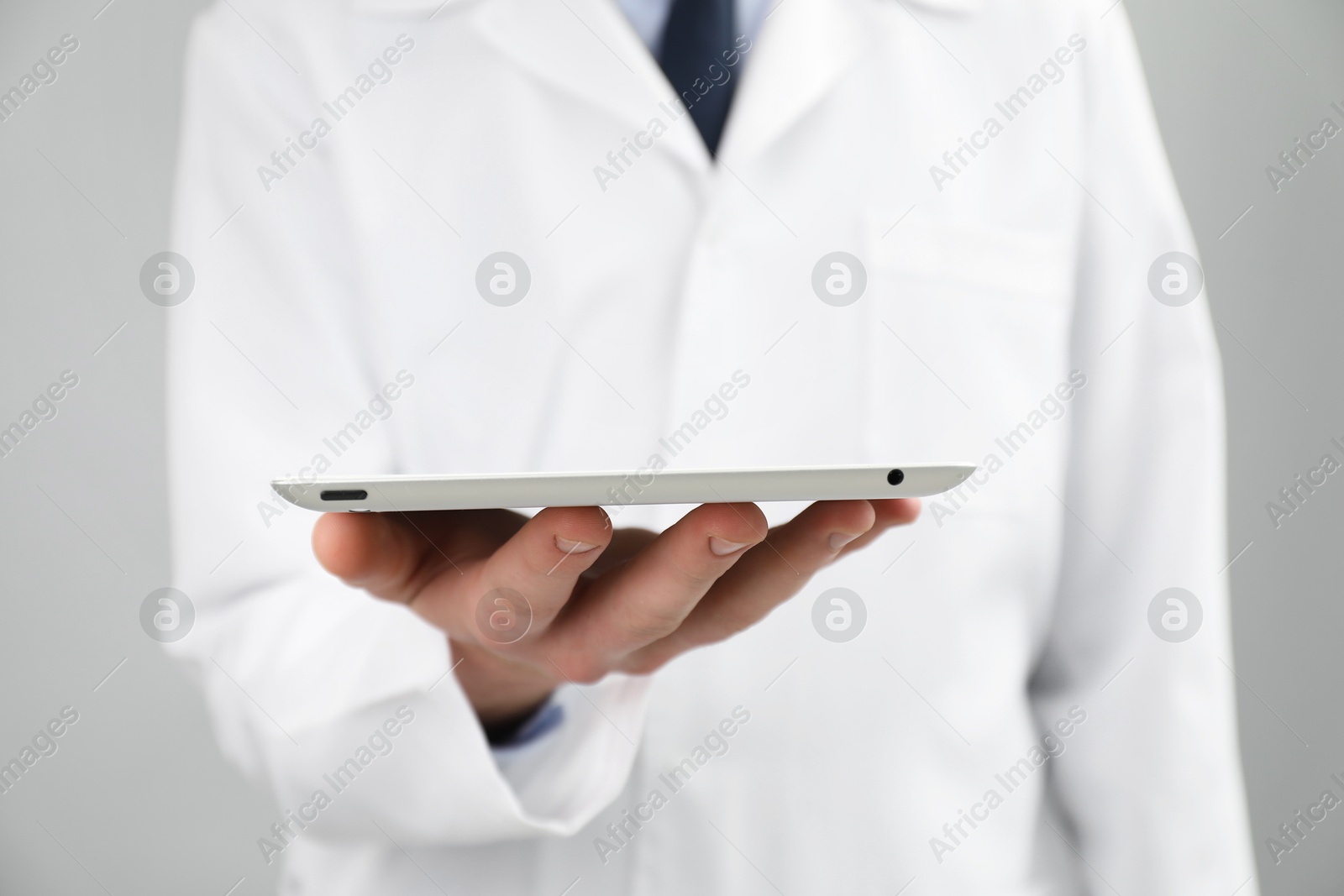 Photo of Doctor with tablet on grey background, selective focus