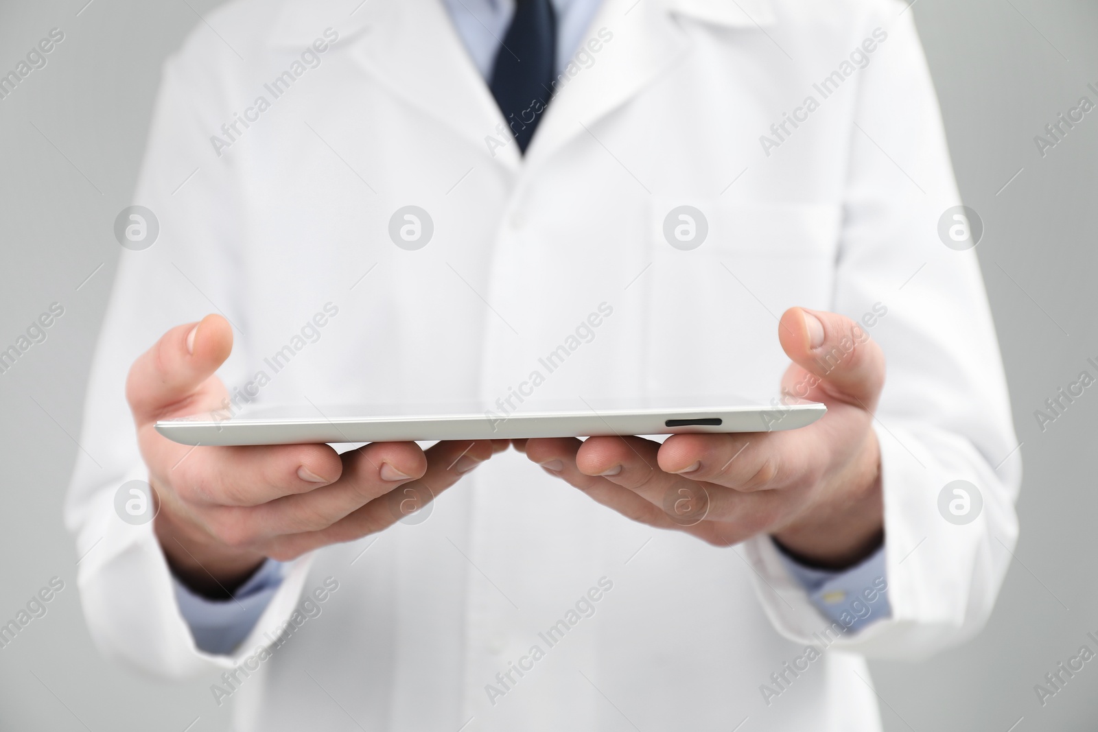 Photo of Doctor with tablet on grey background, selective focus