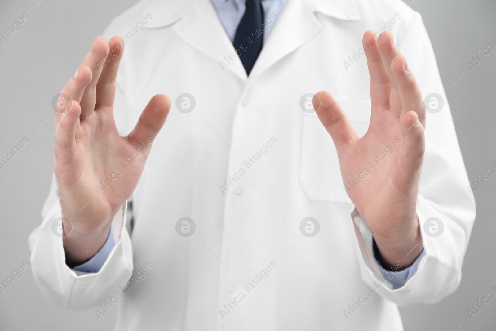 Photo of Doctor holding something on grey background, selective focus