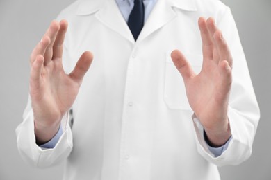 Photo of Doctor holding something on grey background, selective focus