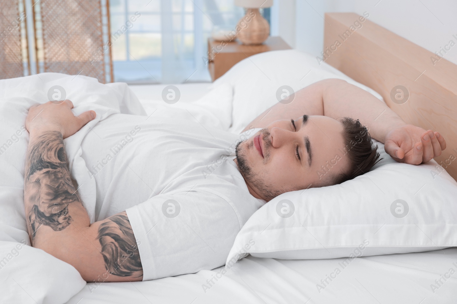 Photo of Bedtime. Handsome man sleeping in bed indoors