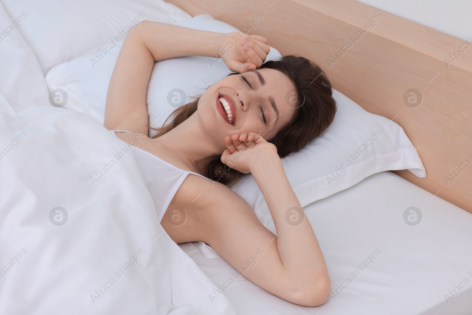 Photo of Bedtime. Happy woman lying in bed indoors