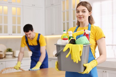Photo of Cleaning service worker holding bucket with supplies in kitchen