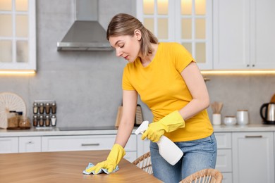 Photo of Professional janitor wearing uniform cleaning table in kitchen