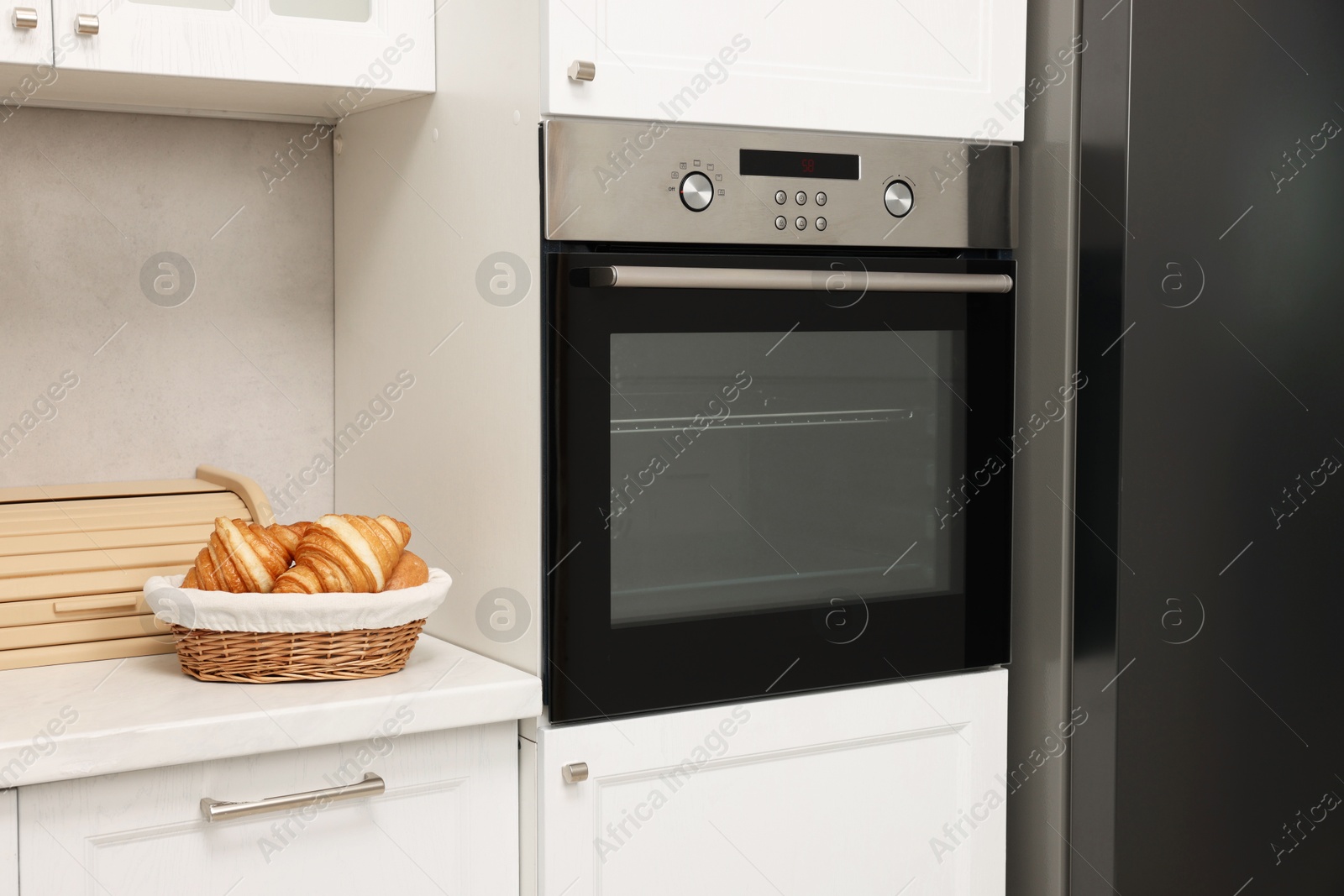 Photo of Electric oven and croissants in kitchen. Cooking appliance