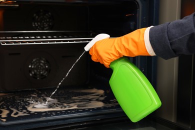 Woman cleaning oven with detergent, closeup view