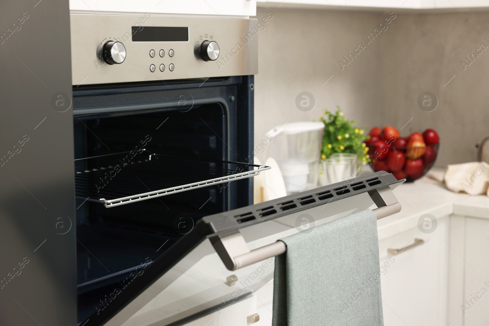 Photo of Open electric oven with towel in kitchen. Cooking appliance