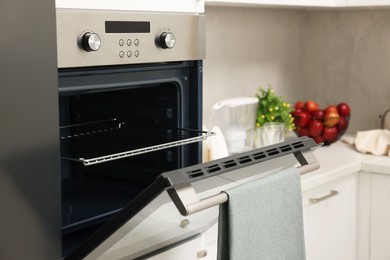 Photo of Open electric oven with towel in kitchen. Cooking appliance