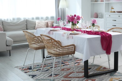 Photo of Beautiful table setting with flowers and rattan chairs in dining room