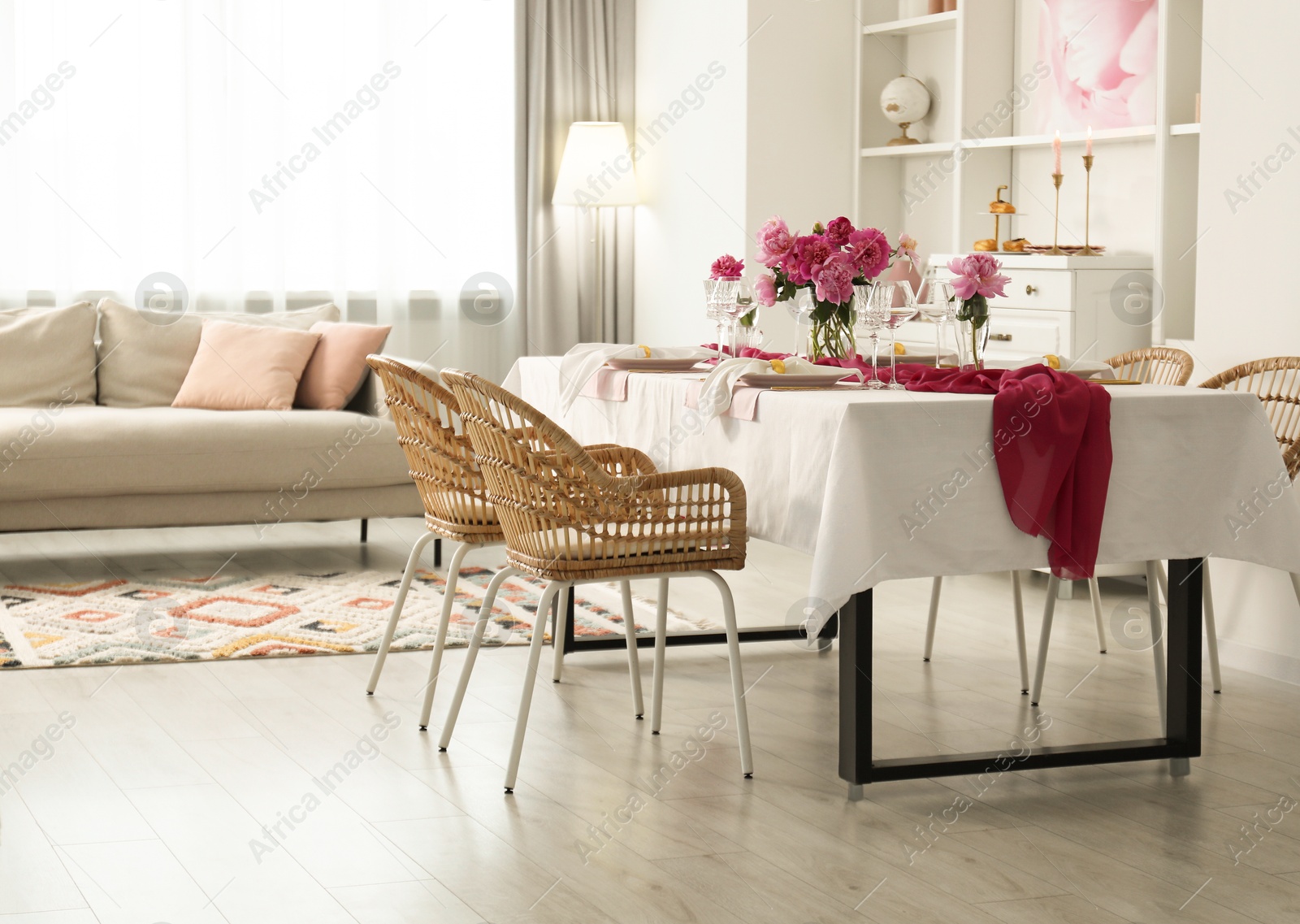 Photo of Beautiful table setting with flowers and rattan chairs in dining room