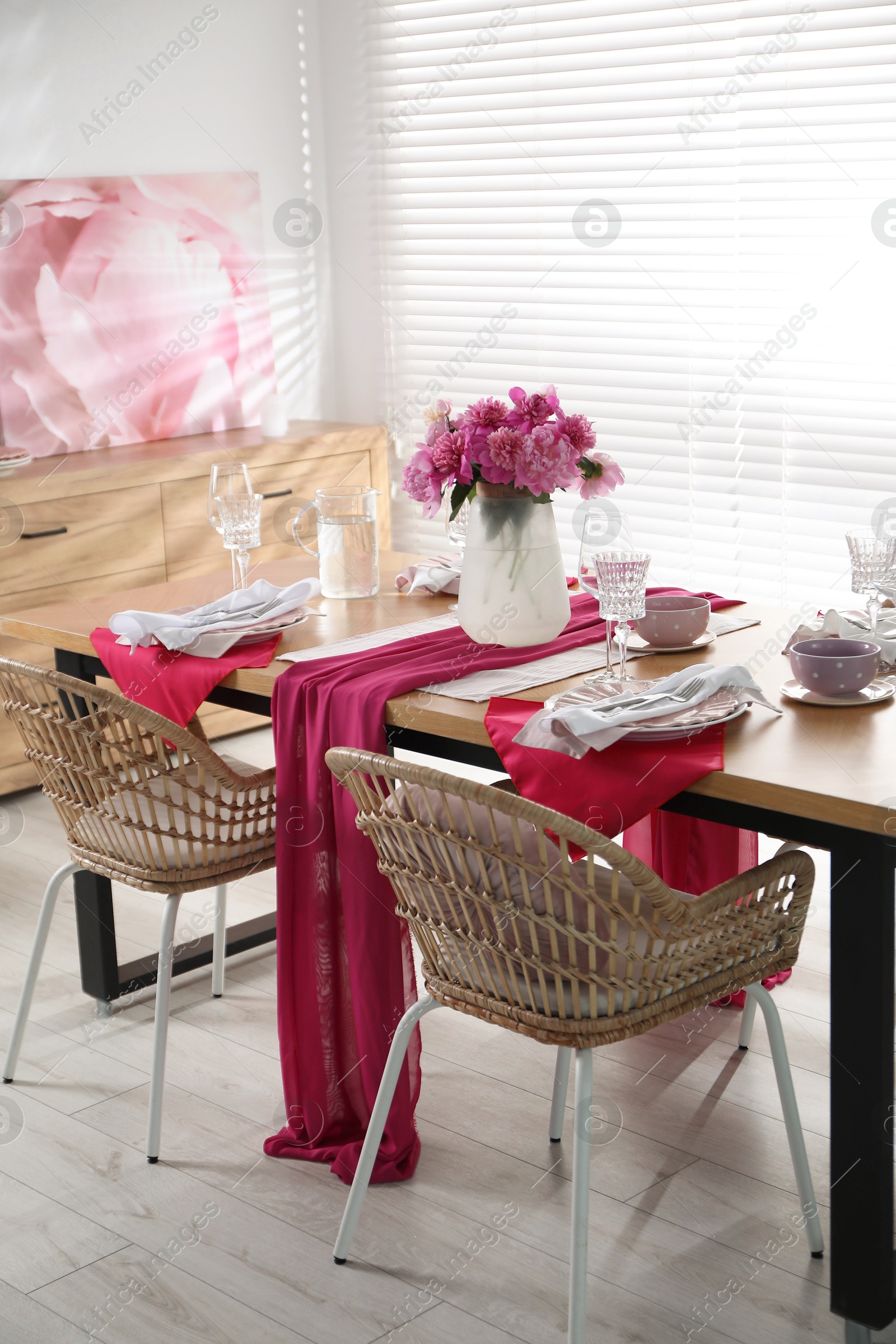 Photo of Pink peonies on table with beautiful setting and rattan chairs in dining room