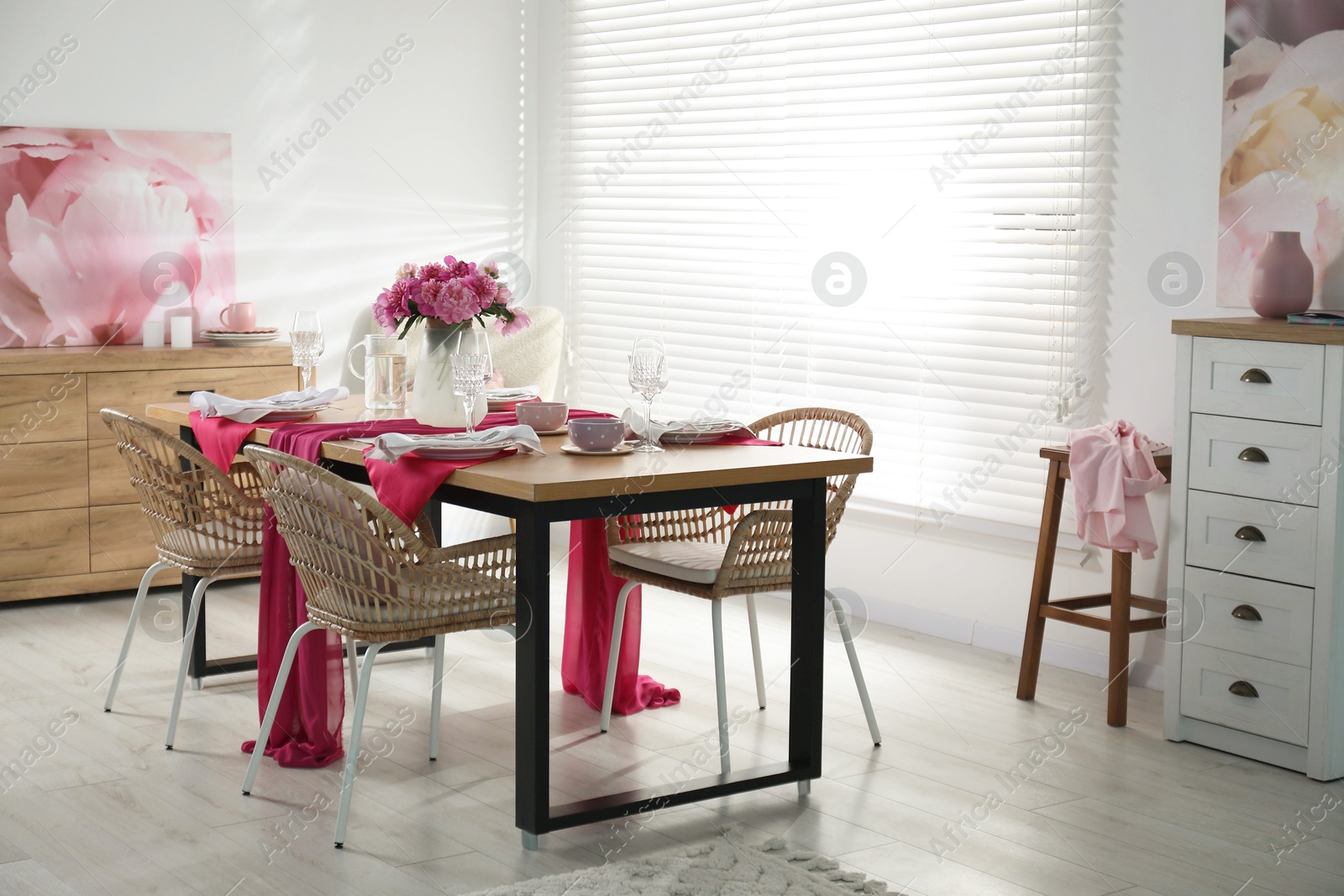 Photo of Pink peonies on table with beautiful setting and rattan chairs in dining room