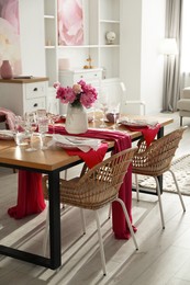 Photo of Pink peonies on table with beautiful setting and rattan chairs in dining room