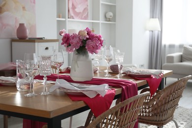 Photo of Pink peonies on table with beautiful setting and rattan chairs in dining room