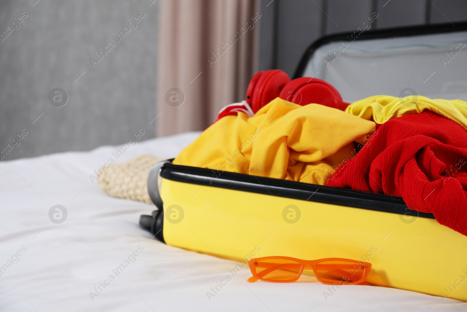 Photo of Open suitcase with traveler's belongings on bed, closeup. Space for text