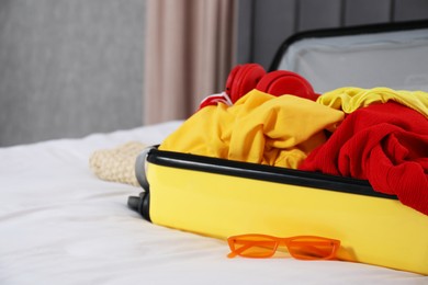 Photo of Open suitcase with traveler's belongings on bed, closeup. Space for text