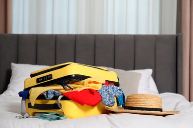 Open suitcase with traveler's belongings on bed