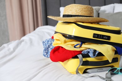 Open suitcase with traveler's belongings on bed, closeup. Space for text