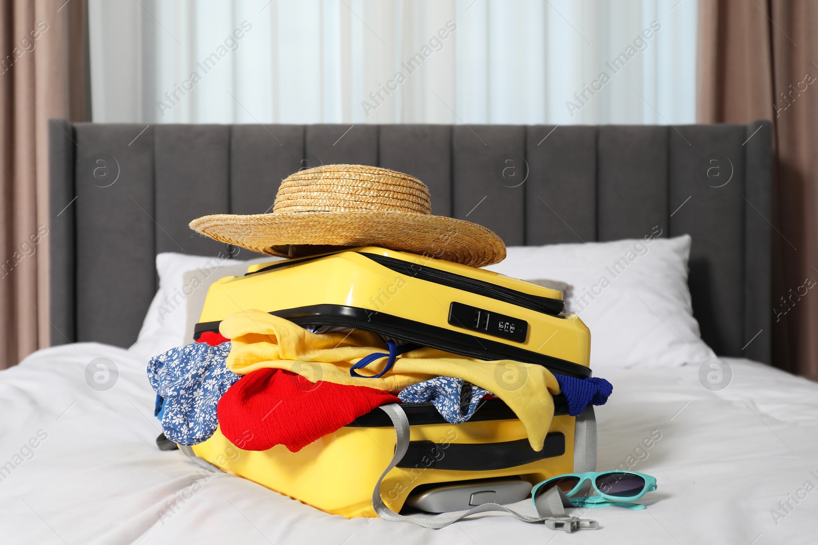 Photo of Open suitcase with traveler's belongings on bed