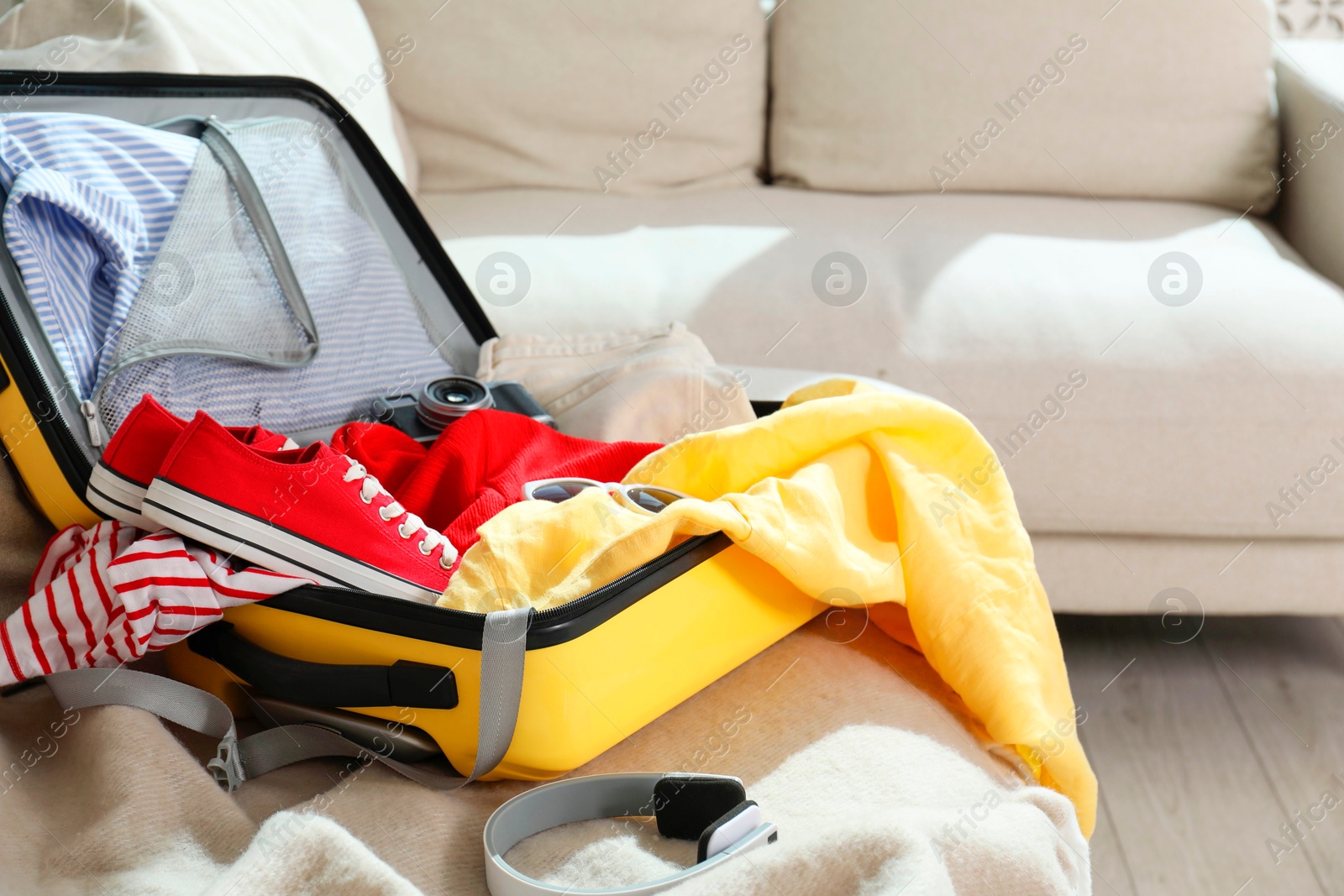 Photo of Open suitcase with traveler's belongings on bed, closeup