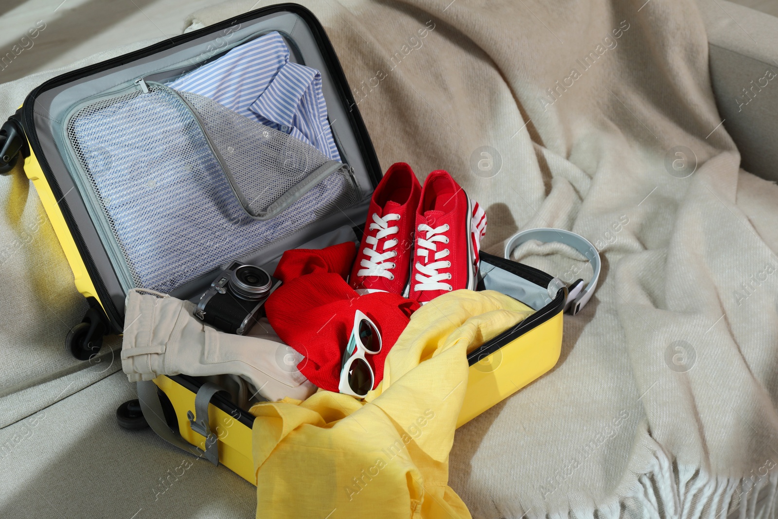 Photo of Open suitcase with traveler's belongings on bed